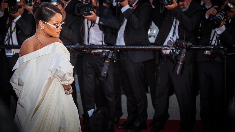 en bild av rihanna som poserar framför reportrar